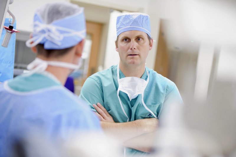 MSK pancreatic and liver cancer surgeon, Peter Allen, speaks with fellow colleagues dressed in their scrubs.